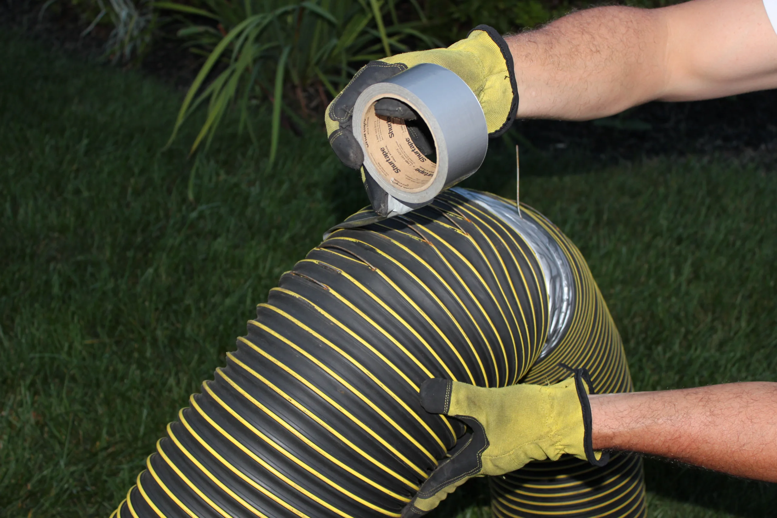 photo of a ripped leaf vacuum hose being repaired with duct tape