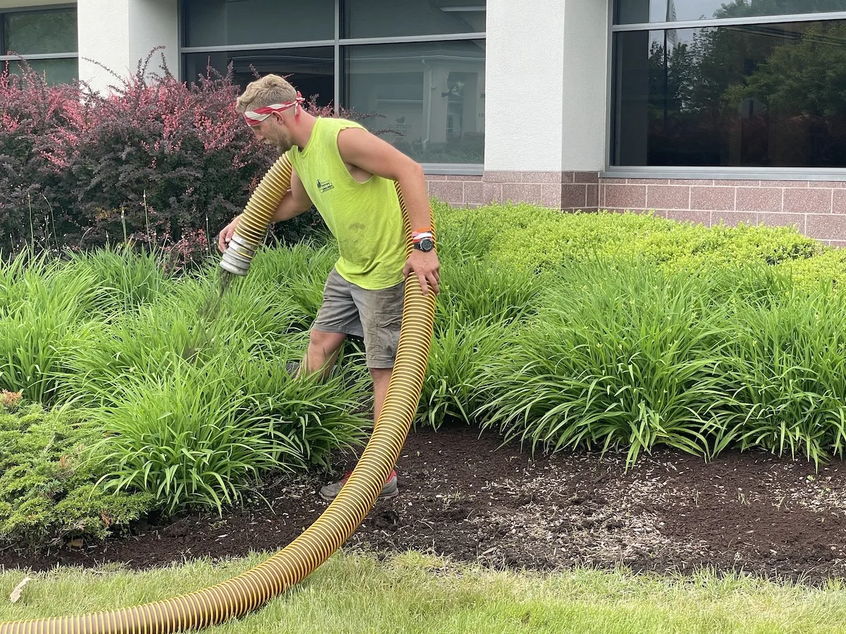 landscaper blowing bark mulch with mulch blower